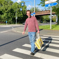 "Thilo mit einer Einkaufstasche auf einem Zebrastreifen"